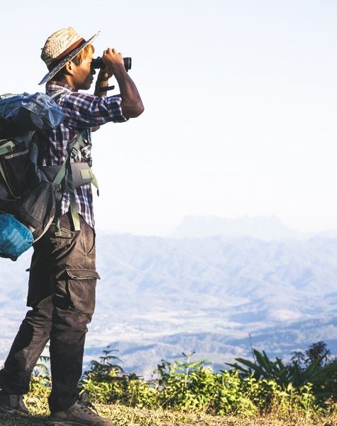 tourist-is-watching-through-binoculars-sunny-cloudy-sky-from-mountain-top_1150-9123